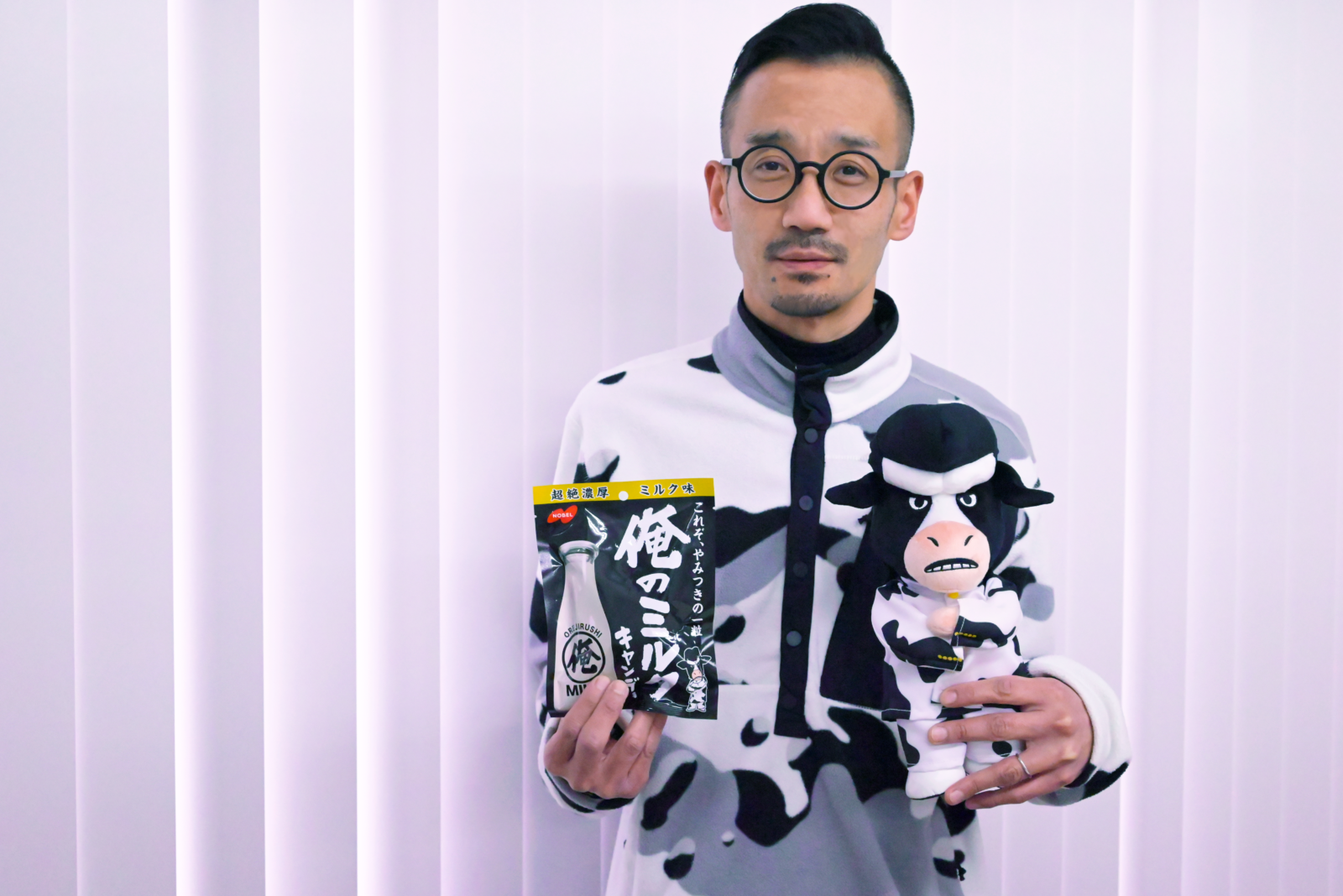 ”俺のミルク”パッケージと俺ミル番長のぬいぐるみを持つ開発者